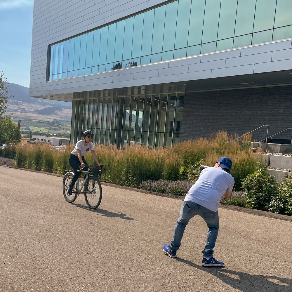 A photographer takes a picture of someone riding a bike on UBCO's campus during a photoshoot